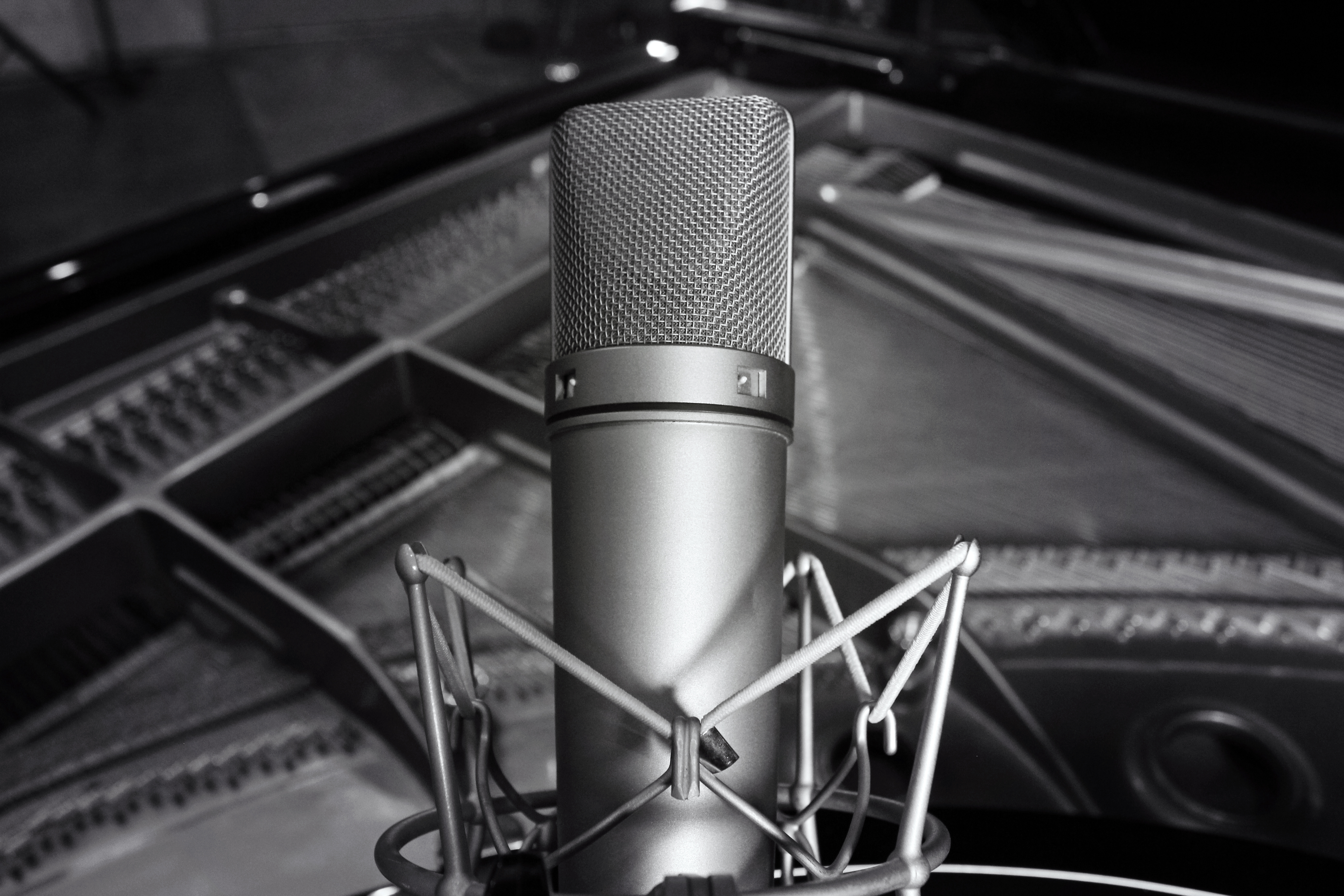 Black and white image of studio microphone foregrouding sound mixing equipment.